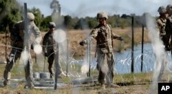 FILE - In this Nov. 16, 2018, photo, members of the U.S. military install multiple tiers of concertina wire along the banks of the Rio Grande near the Juarez-Lincoln Bridge at the U.S.-Mexico border in Laredo, Texas.