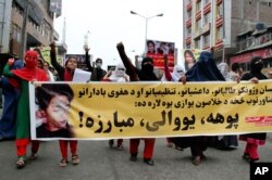 Women march as they hold photos showing ethnic Hazara victims who were allegedly beheaded by the Taliban, in Jalalabad, east of Kabul, Nov. 12, 2015.