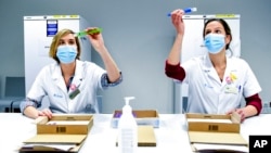 FILE - Health workers inspect vials of the Pfizer-BioNTech COVID-19 vaccine as they are thawed in a lab at the UZ Leuven hospital in Leuven, Belgium, Dec. 27, 2020. 