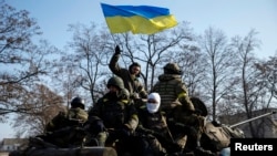 Members of the Ukrainian armed forces ride on an armored personnel carrier near Debaltseve after the signing of a cease-fire agreement in Minsk, Feb. 12, 2015.