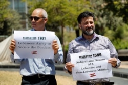 FILE - Anti-Hezbollah protesters hold banners with the U.N. Resolution 1559, which called for disarmament all Lebanese and non-Lebanese militias, during a sit-in in front the UN headquarters in Beirut, July 24, 2020.