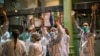 Health workers react as people applaud from their houses in support of the medical staff that are working on the COVID-19 virus outbreak at the main gate of the Hospital Clinic in Barcelona, Spain, March 26, 2020. 