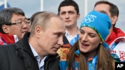 FILE - Russian President Vladimir Putin speaks with Olympic Village Mayor Elena Isinbaeva while visiting the Coastal Cluster Olympic Village ahead of the Sochi 2014 Winter Olympics in Sochi, Russia. 