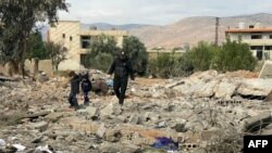 A man and two children walk above debris at the site of an overnight Israeli airstrike in the eastern Lebanese village of al-Qasr, on Nov. 11, 2024. 