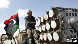 A rebel fighter stands on the back of a pick-up truck mounted with a rocket launcher at a staging post on the road between Ajdabiyah and Brega in Libya, April 9, 2011