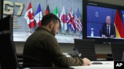 En esta imagen de un video proporcionado por la oficina de prensa de la presidencia de Ucrania, el presidente Volodymyr Zelenskyy, en Kiev, y el canciller alemán Olaf Scholz, en pantalla, durante una conferencia de video de los líderes del G7, el 11 de octubre de 2022.