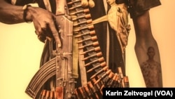 The image of a Dinka woman is reflected in the arm of a Nuer fighter in this photograph from U.S. photographer Tim Freccia's series on South Sudan, "Life and Death."