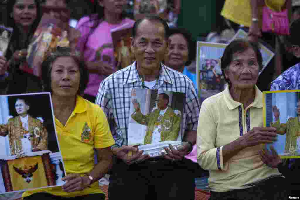 Well-wishers hold pictures of Thailand's King Bhumibol Adulyadej, Dec. 4, 2013,&nbsp;as they camp outside the palace where he is staying in Hua Hin, Prachuap Khiri Khan province, Thailand, a day before his birthday.
