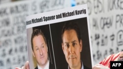 (资料照) 加拿大抗议人士举着加拿大商人迈克尔·斯帕弗（Michael Spavor）和加拿大前外交官康明凯（Michael Kovrig）的头像的标语，抗议中国政府任意拘押这两位加拿大公民。（美联社）