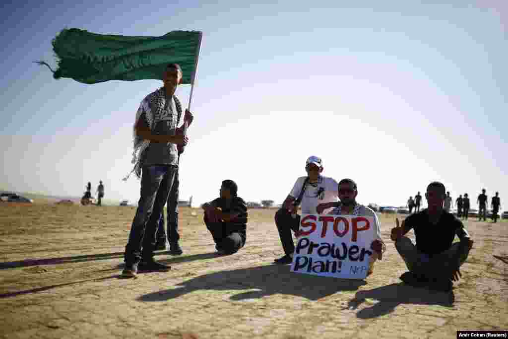 A protester holds a placard as another holds an Islamic movement flag during a demonstration to show their solidarity with Bedouin citizens, near the Bedouin townof Rahat in southern Israel August 1, 2013.