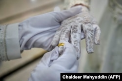 Seorang pengantin pria memasang cincin di jari istrinya saat upacara pernikahan di sebuah masjid di Banda Aceh pada 3 Juni 2020. (Foto: AFP/Chaideer Mahyuddin)