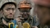 Ukrainian coal miners wait for a bus after exiting the underground of the Zasyadko mine in Donetsk, Ukraine, March 4, 2015.