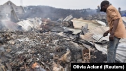 Les habitants ramassent les restes de leurs maisons détruites après l'éruption du volcan du mont Nyiragongo près de Goma, en RDC, le 23 mai 2021.