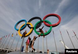 FILE - People pose with Olympics rings at the Olympic Park in Sochi, Russia, Feb. 24, 2014.
