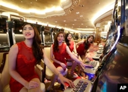 FILE - Casino models pose at the slot machines during the media tour of Solaire Casino in the Philippines. Casino chips are commonly used to launder money because the exchanges quickly become anonymous.