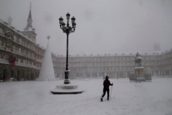 Seorang wanita bermain ski saat melintasi Plaza Mayor di Madrid saat hujan salju lebat di Madrid, Spanyol, Sabtu, 9 Januari 2021.