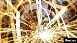 FILE - A worker grinds an iron window frame used in a dairy machine at a manufacturing unit in the western Indian city of Ahmedabad, India.