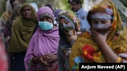 FILE - In this Saturday, April 11, 2020 file photo, women wait for their turn to receive cash in Islamabad, Pakistan during a government-imposed nationwide lockdown. (AP Photo/Anjum Naveed)