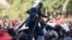 Ugandan pop star turned opposition MP, Robert Kyagulanyi, is helped by his supporters as he delivers a speech outside his home in Kampala, Uganda, after returning from the United States on Sept. 20, 2018.