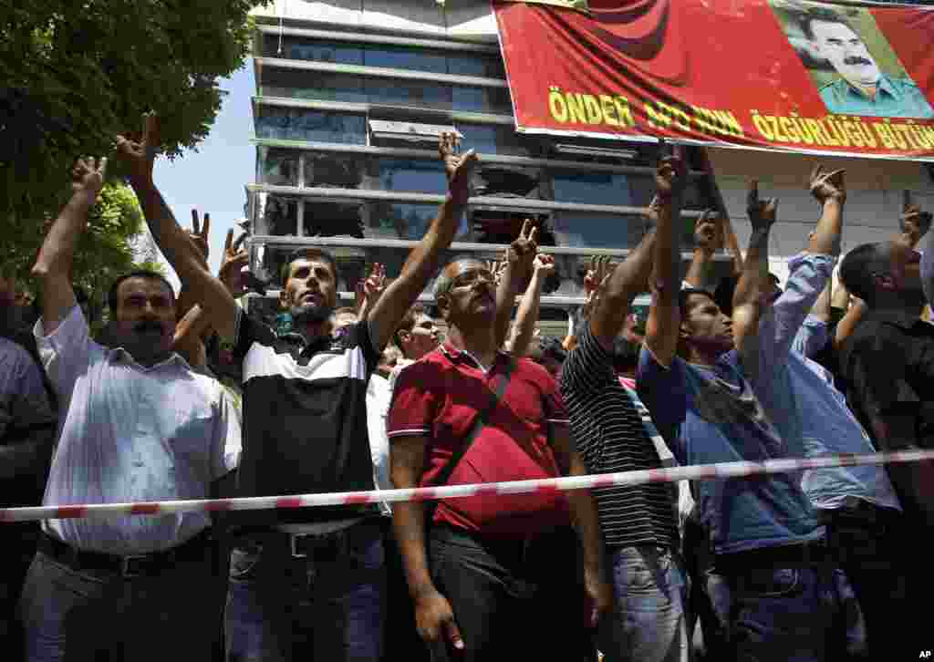 Mourners flash the V-sign as they gather at the site of Monday&#39;s explosion in the Turkish town of Suruc near the Syrian border, July 21, 2015.