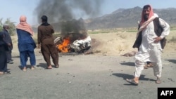 Pakistani local residents gather around a burning vehicle hit by a U.S. drone strike, May 21, 2016. Afghan Taliban Mullah Akhtar Mansoor was the target of the drone near Dalbandin, Baluchistan, Pakistan.