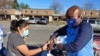 Clint Mitchell, the principal of Mount Vernon Woods Elementary School in Alexandria, Virginia, hands a turkey to a woman who stopped by to pick up food for a Thanksgiving meal. (Deborah Block/VOA)