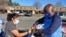Clint Mitchell, the principal of Mount Vernon Woods Elementary School in Alexandria, Virginia, hands a turkey to a woman who stopped by to pick up food for a Thanksgiving meal. (Deborah Block/VOA)