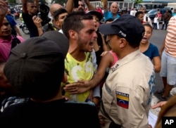 A man waiting in line at a grocery store argues with a Bolivarian National Police officer as he and others wait for food to arrive to the store in Caracas, Venezuela, June 8, 2016.