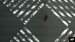 A woman walks through an empty pedestrian crossing in the Ginza shopping district April 3, 2020, in Tokyo. 