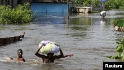 FILE - People wade through a flood with their belongings after their houses were submerged in the Amassoma community in Bayelsa state, Nigeria, Oct. 6, 2012.