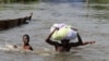 FILE - People wade through a flood with their belongings after their houses were submerged in the Amassoma community in Bayelsa state, Nigeria, Oct. 6, 2012.
