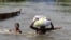 FILE - People wade through a flood with their belongings after their houses were submerged in the Amassoma community in Bayelsa state, Nigeria, Oct. 6, 2012.