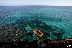 FILE - Philippine Marine, right, swims in the waters of Second Thomas Shoal in the South China Sea.