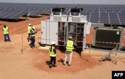 FILE - Technicians operate electrical cabinets, Oct. 22, 2016, during the opening ceremony of a new photovoltaic energy production site in Bokhol, Senegal. It was one of sub-Saharan Africa's largest solar energy projects.