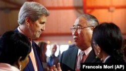 时任美国国务卿克里和中国气候特使解振华在联合国气候变化框架公约签约国第21次会议上交谈。（2015年12月12日）