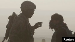 FILE - A U.S. soldier and a translator are silhouetted as they talk to each other at a joint U.S. military and Afghan police checkpoint in Nangarhar province, eastern Afghanistan, March 7, 2012. 