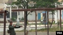 Seorang anggota pasukan Suriah mengarahkan senjatanya ke arah demonstran anti pemerintah di kota Hama (21/5).