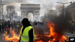 A yellow vest protester walks past a fire on Champs Elysees avenue in Paris, France, March 16, 2019.