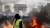 A yellow vest protester walks past a fire on Champs Elysees avenue in Paris, France, March 16, 2019.