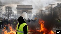 A yellow vest protester walks past a fire on Champs Elysees avenue in Paris, France, March 16, 2019.