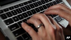 FILE- A person types on a laptop keyboard in North Andover, Mass, June 19, 2017. 