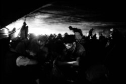 Even during the day, it is often dark under the bridge in Pul e Sukhta. A man with a head torch prepares his drugs. (Maciej Stanik/VOA)