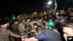 Pro-democracy protesters pull steel barricades in front of police as they try to march forward during a rally in Bangkok, Thailand, Feb. 13,2021. 