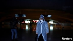 A man wearing a face mask and a plastic raincoat is seen at a railway station of Wuhan, China, March 28, 2020.
