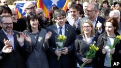 FILE - Former Catalan leader Carles Puigdemont, center, holds a bunch of flowers as he and supporters sing after a news conference in Berlin, Germany, Saturday, April 7, 2018.