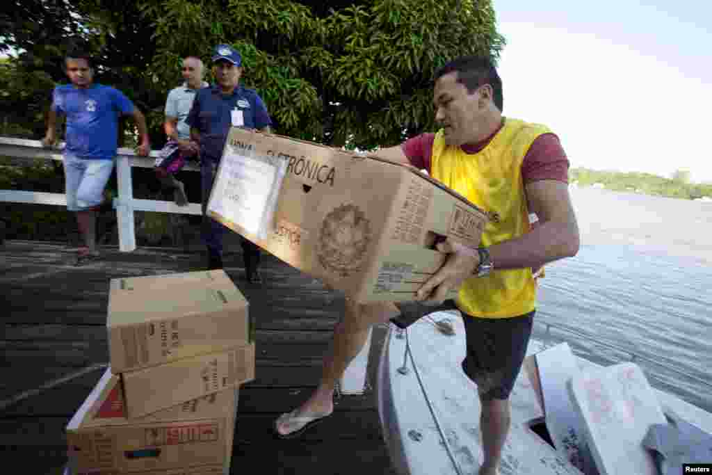 An election official carries a box of electronic ballots from a boat to a community on Ilha Grande island across the Amazon River from Belem, Oct. 5, 2014.