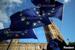 Seorang demonstran mengibarkan bendera Uni Eropa di luar Gedung Parlemen di London, Inggris, 13 September 2017. (Foto: REUTERS/Hannah McKay)
