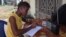 17-year- old Doris Ansumana listening to a radio school program in Freetown, Sierra Leone, Oct, 20,2014- (N.deVries/VOA).