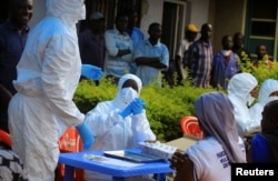 Congolese and WHO officials wear protective suits as they prepare equipment before the launch of vaccination campaign against the deadly Ebola virus near Mangina village, near Beni in North Kivu province, DRC, Aug. 8, 2018.