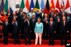 U.S. President Barack Obama, front row third from left, Chinese President Xi Jinping, second from right, and other leaders wave as they pose for a group photo session for the G-20 Summit held at the Hangzhou International Expo Center in Hangzhou.